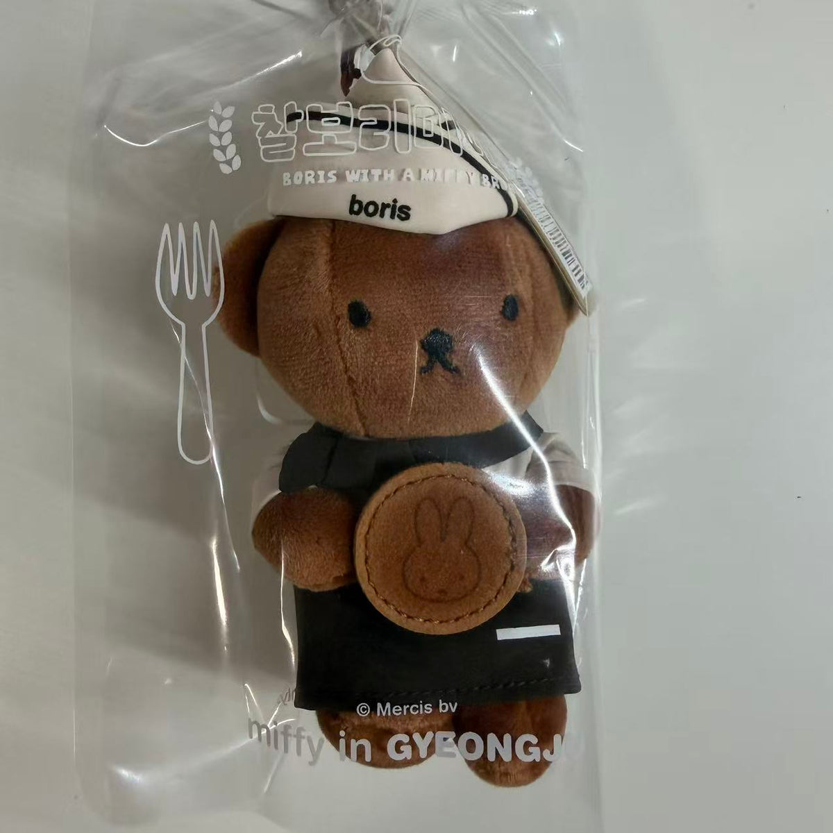 Gyeongju Boris baking plush mascot in a checked baker cap and apron, holding a bunny-shaped bread detail.