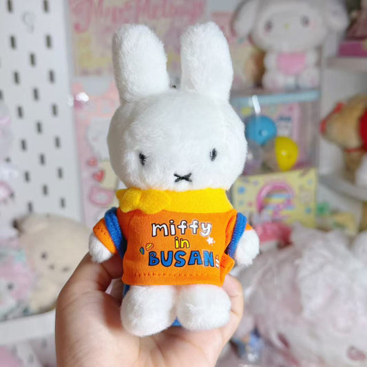 Front view of the Busan Miffy plush mascot in an orange outfit with a yellow collar.