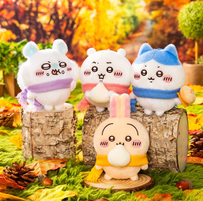 Chiikawa, Hachiware, Usagi and Momonga scarf plush bag charm collection displayed together on logs in an autumn forest scene.