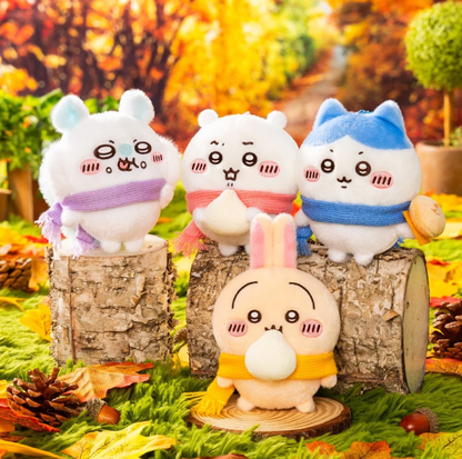 Chiikawa, Hachiware, Usagi and Momonga scarf plush bag charm collection displayed together on logs in an autumn forest scene.