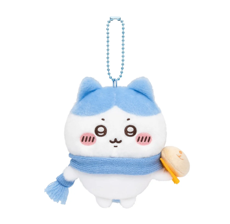 Hachiware plush bag charm wearing a blue scarf and holding a tan bun at his side, with a blue ball chain.