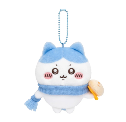 Hachiware plush bag charm wearing a blue scarf and holding a tan bun at his side, with a blue ball chain.