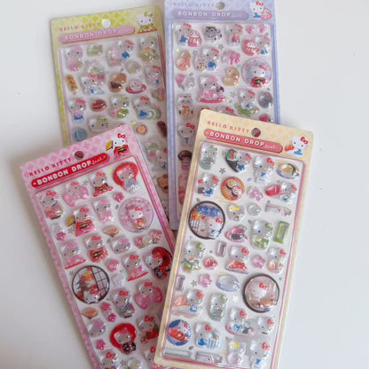 Four Hello Kitty BONBON DROP Japanese motif 3D sticker sheets displayed together in green, purple, yellow and pink-backed red designs.