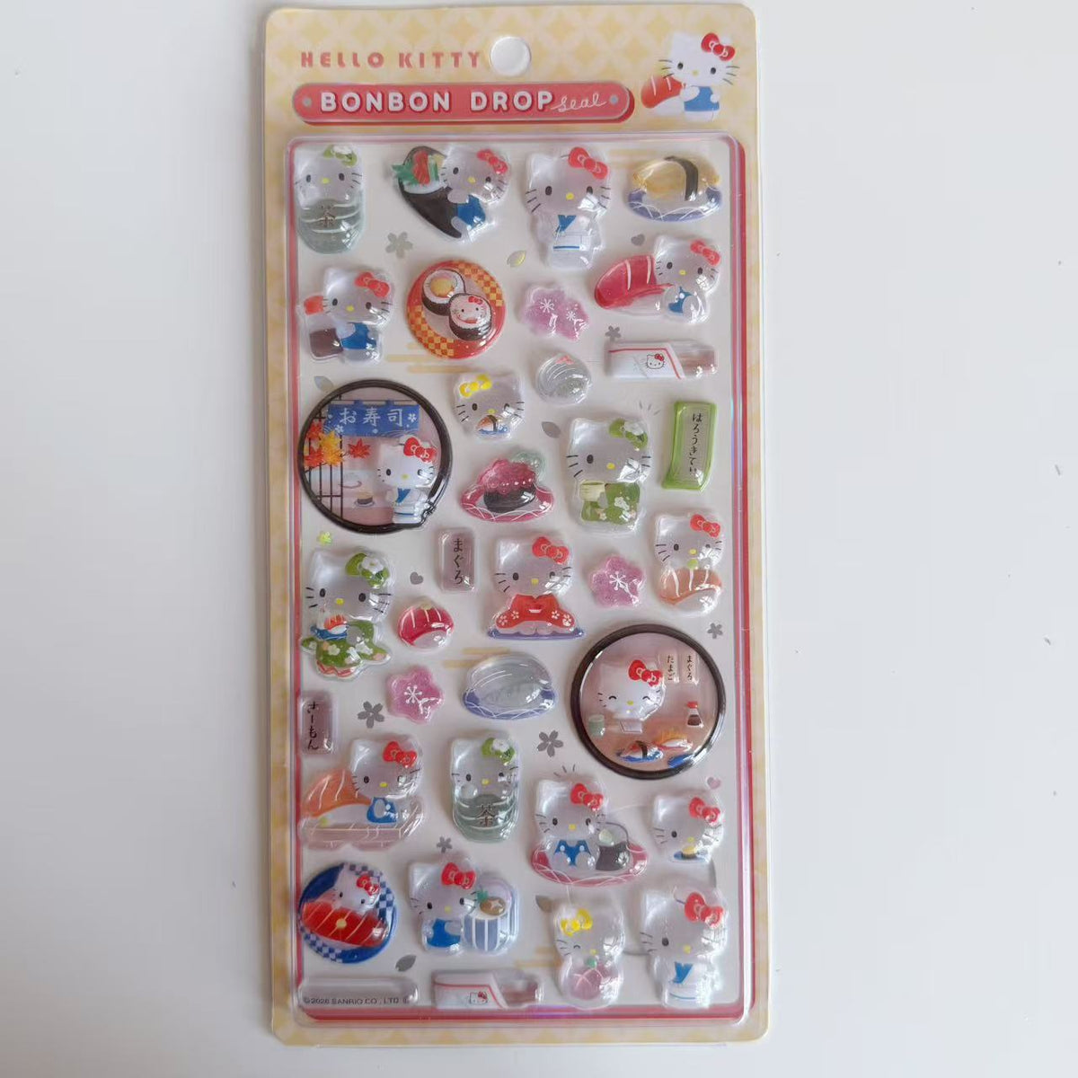 Hello Kitty BONBON DROP Sushi 3D sticker sheet in yellow packaging with sushi, tea and Japanese restaurant scenes.