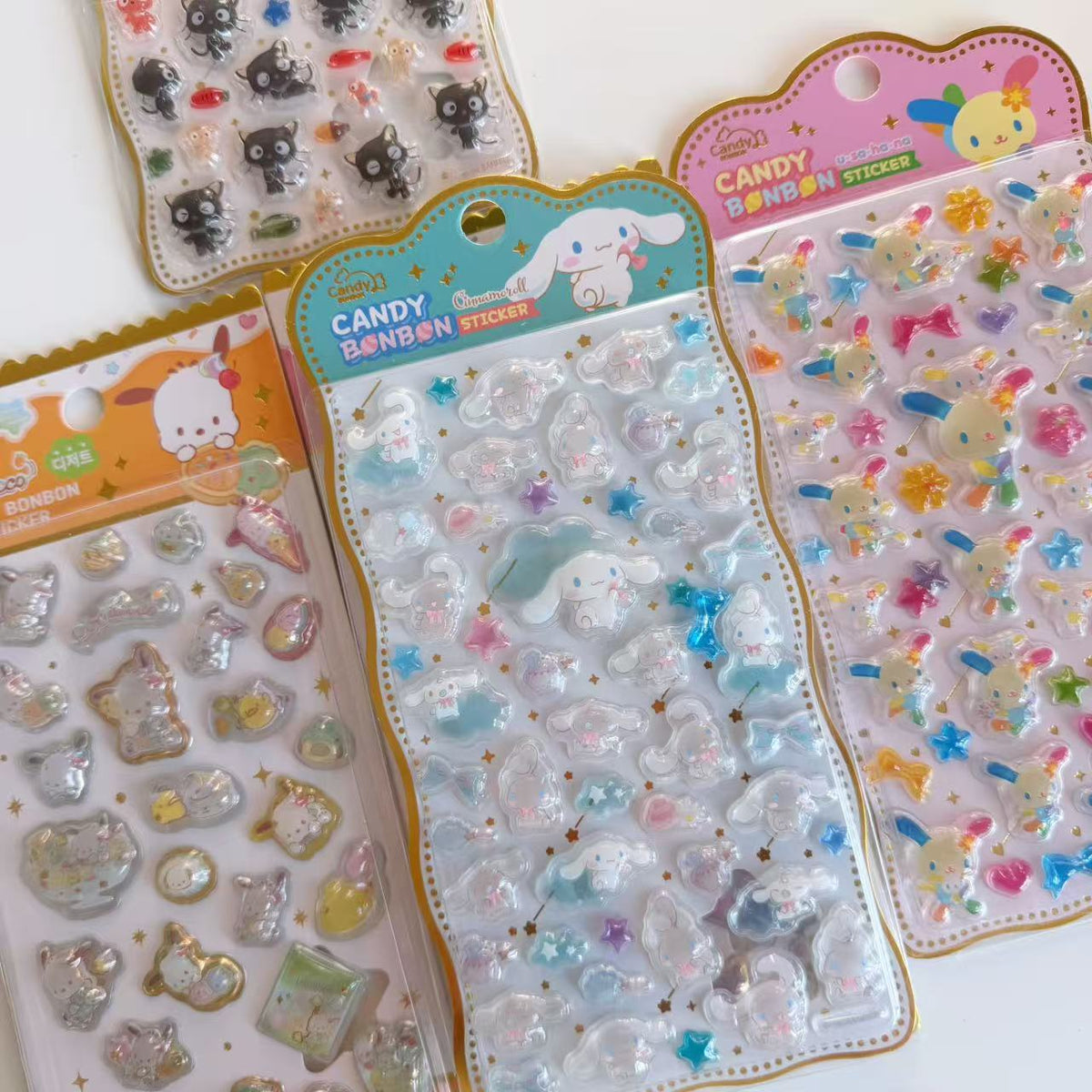 Close-up of glossy raised Candy BONBON stickers, with Cinnamoroll in the centre, Usahana on the right, Pochacco on the left and part of Chococat above.
